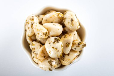 Beyaz arka planda beyaz bir kasede konserve sarımsak.