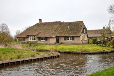 GIETHOORN, NETHERLANDS - tipik Hollanda ilçe tarafı evler ve bahçeler su kanalları alng