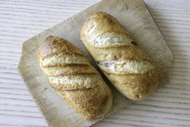 Tahta kesme tahtasının üzerinde iki kabuklu altın kahverengi ekmek - üst görünüm.