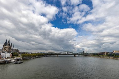 Köln Katedrali ve Almanya 'daki Ren nehri kıyısındaki Hohenzollern köprüsü üzerinde bulutlu bir gün..