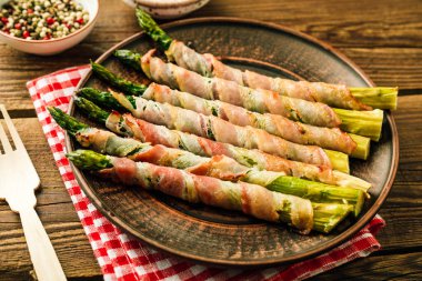 Domuz pastırmasında pişmiş kuşkonmaz. Ahşap arka planda atıştırmalık. Yüksek kalite fotoğraf