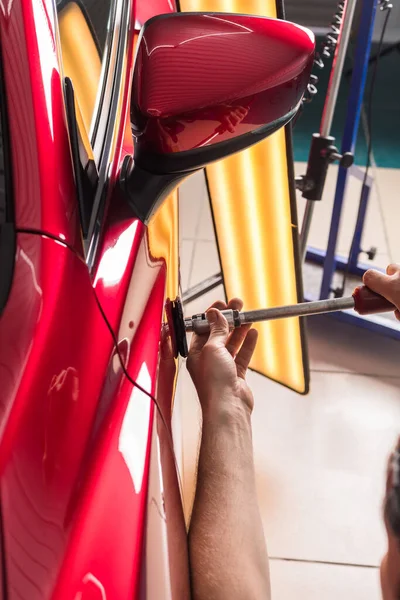 De technicus verwijdert deuken op de auto met behulp van de methode zonder te schilderen. PDR. Reparatie van carrosserie. — Stockfoto