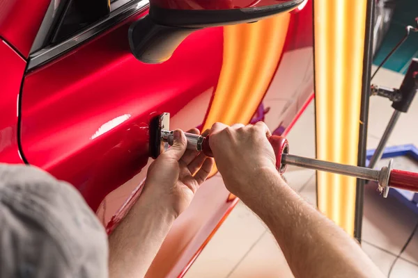 Teknikern tar bort bucklor på bilen med hjälp av metoden utan att måla. PDR. Reparation av bilkaross. — Stockfoto