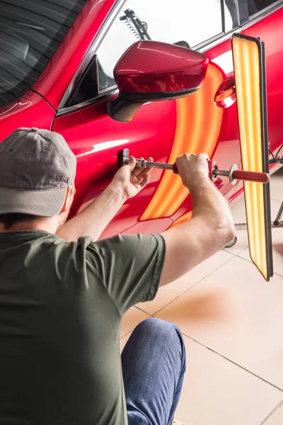 De technicus verwijdert deuken op de auto met behulp van de methode zonder te schilderen. PDR. Reparatie van carrosserie. — Stockfoto