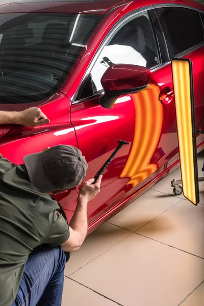 O técnico remove amassados no carro usando o método sem pintura. PDR. reparação do corpo do carro. — Fotografia de Stock