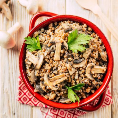 Tahta zemin üzerinde seramik bir tencerede mantarlı karabuğday lapası. Yüksek kalite fotoğraf