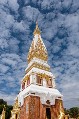 Phra That Phanom, altın oymaları ve beyaz mimarisi olan ikonik Budist ahmak, parlak mavi gökyüzüne karşı yükseliyor. Kutsal Tayland tapınağı simgesi, zengin kültür mirası ve ruhsal atmosfer