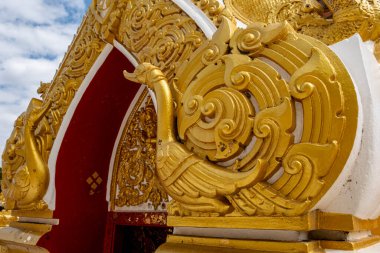 Phra That Phanom, altın oymaları ve beyaz mimarisi olan ikonik Budist ahmak, parlak mavi gökyüzüne karşı yükseliyor. Kutsal Tayland tapınağı simgesi, zengin kültür mirası ve ruhsal atmosfer