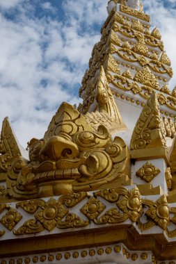 Phra That Phanom, altın oymaları ve beyaz mimarisi olan ikonik Budist ahmak, parlak mavi gökyüzüne karşı yükseliyor. Kutsal Tayland tapınağı simgesi, zengin kültür mirası ve ruhsal atmosfer