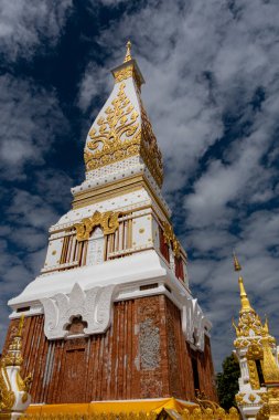 Phra That Phanom, altın oymaları ve beyaz mimarisi olan ikonik Budist ahmak, parlak mavi gökyüzüne karşı yükseliyor. Kutsal Tayland tapınağı simgesi, zengin kültür mirası ve ruhsal atmosfer