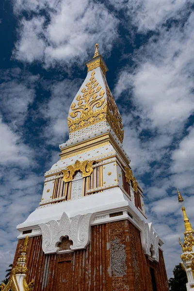 Phra That Phanom, altın oymaları ve beyaz mimarisi olan ikonik Budist ahmak, parlak mavi gökyüzüne karşı yükseliyor. Kutsal Tayland tapınağı simgesi, zengin kültür mirası ve ruhsal atmosfer