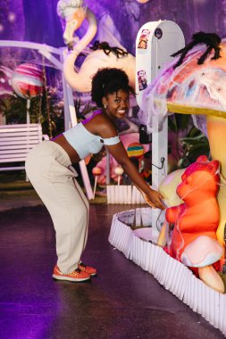 Gülümseyen genç kadın renkli, ürkütücü bir Cadılar Bayramı sahnesinde poz veriyor.