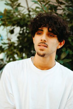 Beyaz gömlekli genç patenci şehirde paten yaptıktan sonra dışarıda dinleniyor.