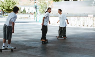 Modern şehir meydanında birlikte dolaşan çok ırklı patenci grubu.
