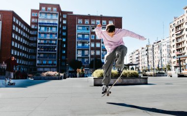Şehir kaykaycısı açık mavi gökyüzünün altında şık bir numara yapıyor.