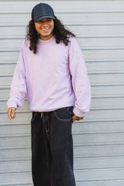 Kameraya gülümseyen genç patenci pastel bir kazak ve şapka giyiyor.