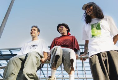 Üç genç patenci gülüyor ve serinliyor açık gökyüzünün altında