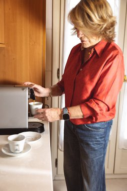 Yaşlı kadın evdeki mutfağında bir fincan kahve hazırlıyor.