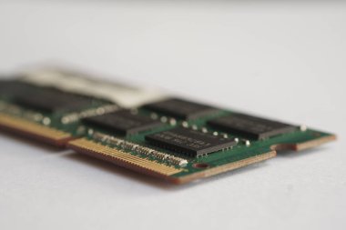 DDR3 RAM modülünün yakın açılı görüntüsü, altın bağlantı iğneleri ve yüzeye monte edilmiş bileşenleri vurguluyor. Elektronik mühendisliği için ayrıntılı odaklı çekim.