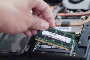 Bilgisayardaki bozuk veya eski bir RAM modülünü değiştiren bir bilgisayar teknisyeninin aksiyon görüntüsü. Donanımsal sorun çözmede önemli bir adım.