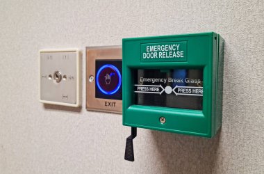 Acil çıkış kapısı kırma ünitesi, modern bir bina duvarındaki anahtarsız çıkış düğmesi erişim kontrol sistemlerinin yanında..