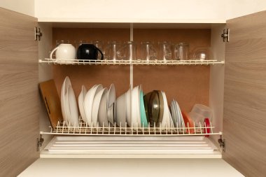 Tabaklar, şeffaf bardaklar ve tabaklar ile mutfak dolabını aç