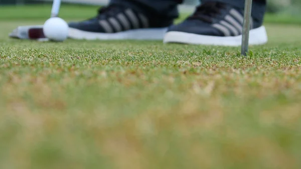 Jugador de golf poniendo pelota en el agujero, solo pies y hierro para ser visto —  Fotos de Stock