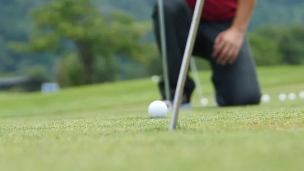 Jugador de golf poniendo pelota en el agujero, solo pies y hierro para ser visto —  Fotos de Stock