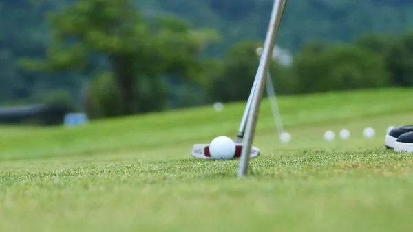 Golf player putting ball into hole, only feet and iron to be seen — Stock Photo, Image