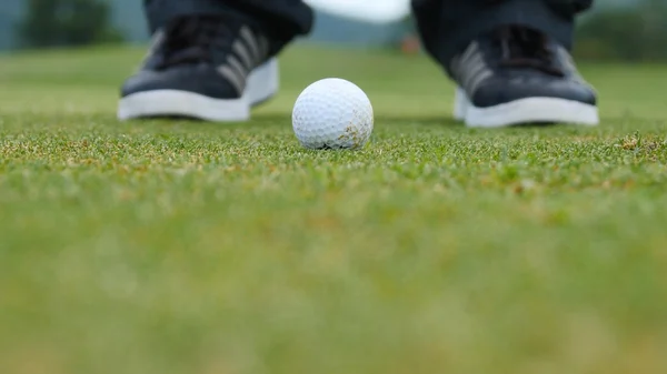 Golf oyuncu topu deliğe, sadece ayak ve demir görülecek koyarak