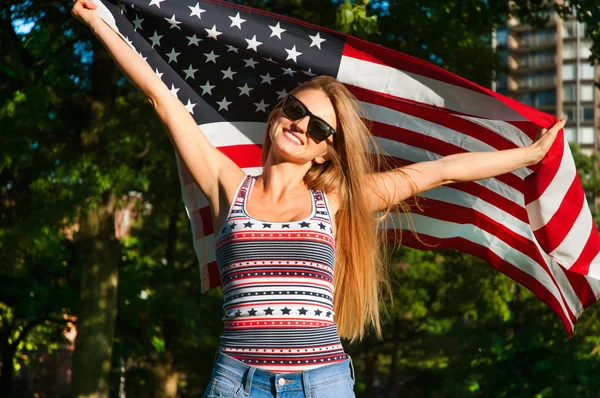 Jovem mulher patriota feliz segurando a bandeira dos Estados Unidos — Fotografia de Stock