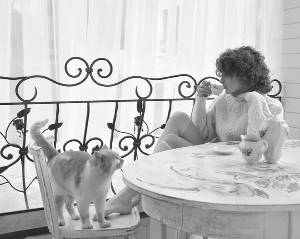 Vrouw blij krullend haar glimlachend en knuffelen met rode kat — Stockfoto