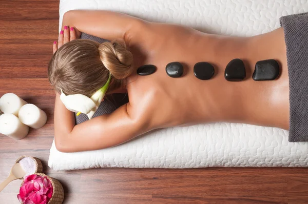Tratamientos de belleza, una mujer que se relaja en un spa de salud mientras recibe un tratamiento con piedras calientes y masajes — Foto de Stock