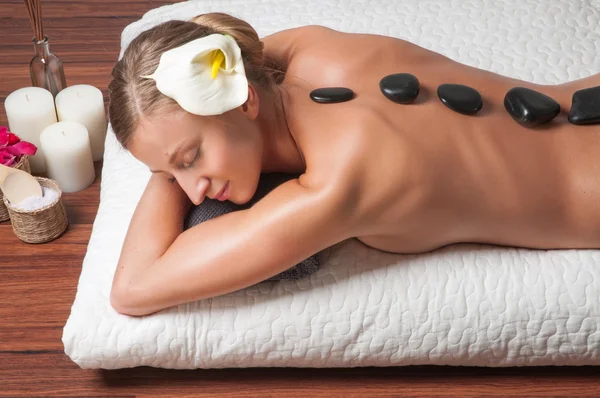 Masaje de piedra. Hermosa mujer consiguiendo spa piedras calientes masaje en el salón de spa . —  Fotos de Stock