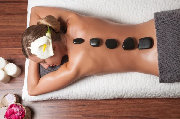 Masaje de piedra. Hermosa mujer consiguiendo spa piedras calientes masaje en el salón de spa . — Foto de Stock