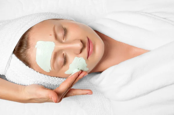 Косметические процедуры. Женщина надевает маску на лицо в спа — стоковое фото
