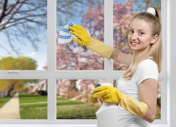 Уборка, женщина моет окно моющим средством — стоковое фото