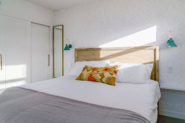 Parlak yatak odası, modern çöl dekorlu yatak başlığı, lambalar, yatak ve yastık. Joshua Tree, Kaliforniya