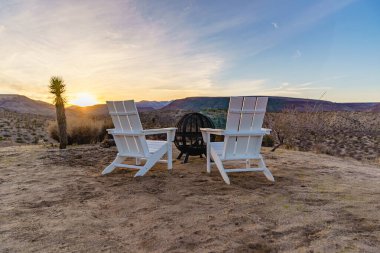 Beyaz Adirondack sandalyeler ve ateş çukuru. Kaliforniya, Yucca Vadisi 'nde çölün batışını izliyorum..