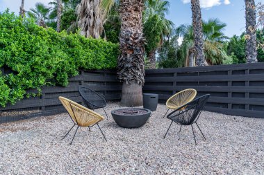 Ateş çukuru, Acapulco sandalyeleri, gündüz vakti palmiye ağaçları olan açık veranda sohbet alanı.