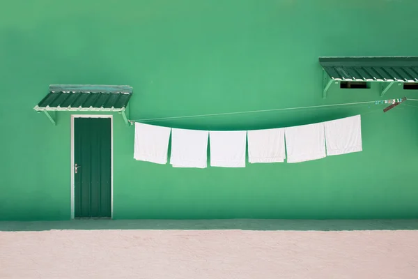 Wäscheleine mit weißen Handtüchern vor grüner Wand mit grüner Tür — Stockfoto