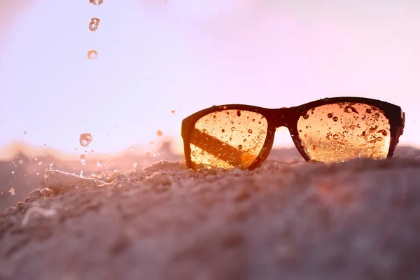 Жовті сонцезахисні окуляри піщаний пляж з бризкою — стокове фото