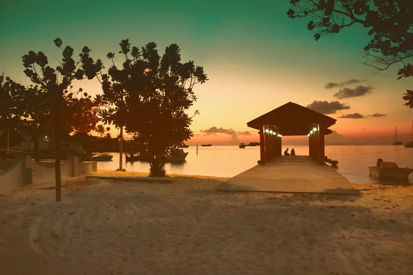 Пляж рай Мальдіви на рожевому заході сонця, світське світло в ресторані над водою, з копл і човни романтичне місце — стокове фото