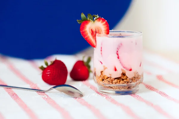 Bardak taze soğuk yoğurt ve granola yulaf ezmesi ile mavi arka plan — Stok fotoğraf