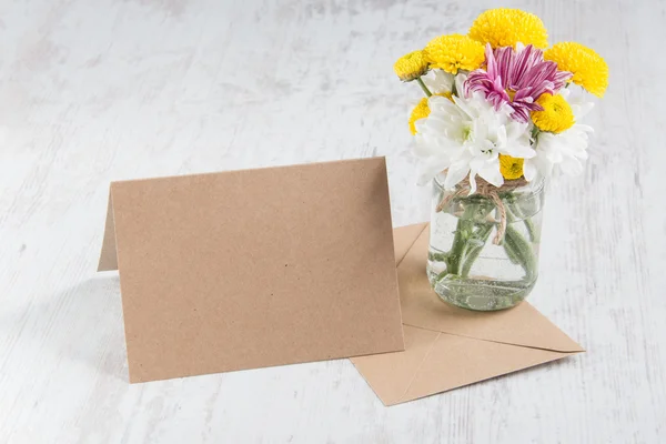 Весенний букет цветов в вазе с карточкой и конвертом на белом деревенском фоне — стоковое фото