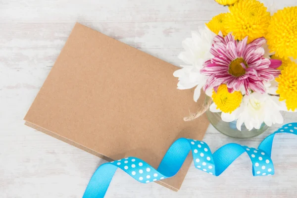 Bukiet kwiatów w wazonie słoik z Uwaga karty, koperty i niebieską wstążką na białym tle rustykalnym drewna — Zdjęcie stockowe