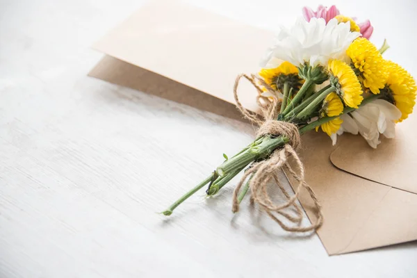 Bukiet kwiatów z Uwaga karty i koperty na białym tle rustykalnym drewna — Zdjęcie stockowe