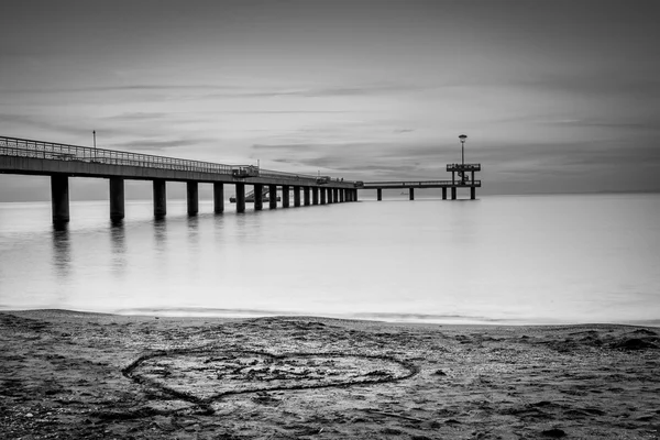 Východ slunce nad mořem most. Srdce v písku. — Stock fotografie