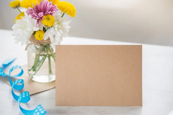 Bukiet kwiatów w wazonie słoik z Uwaga karty, koperty i niebieską wstążką na białym tle rustykalnym drewna — Zdjęcie stockowe