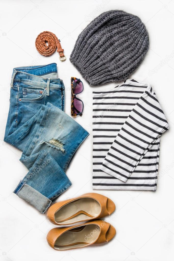 Collage of female clothing set.  Ripped jeans, striped blouse, brown high heels shoes and accessories over white wood background.
